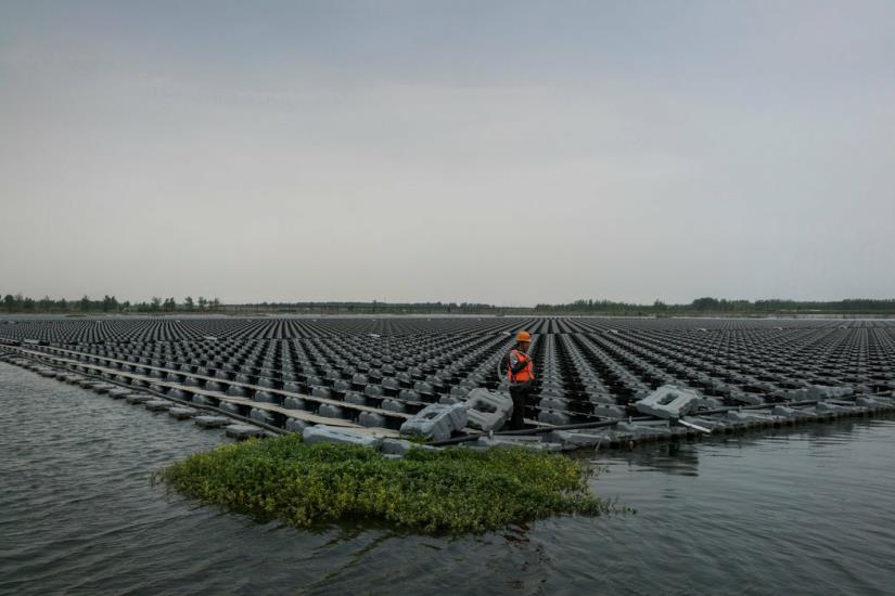 Un trabajador de Sungrow conecta páneles solares flotantes en un lago creado tras el derrumbe de minas de carbón abandonadas en Liulong, China. Credit Adam Dean New York Times